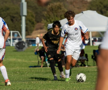 Young men playing soccer on a grassy field