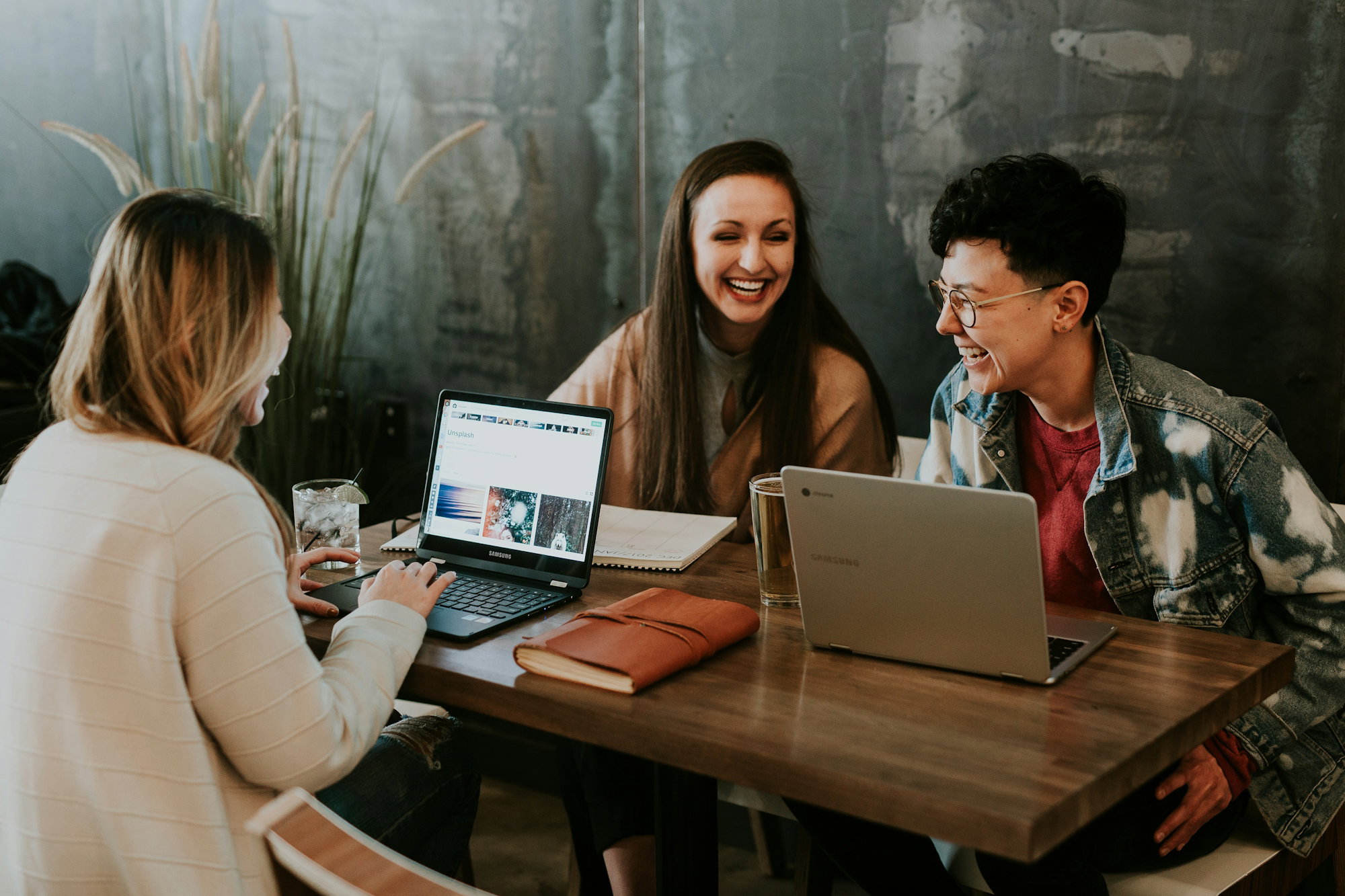 three-people-sitting-in-front-of-table-laughing-together.jpg three people sitting in front of table laughing together